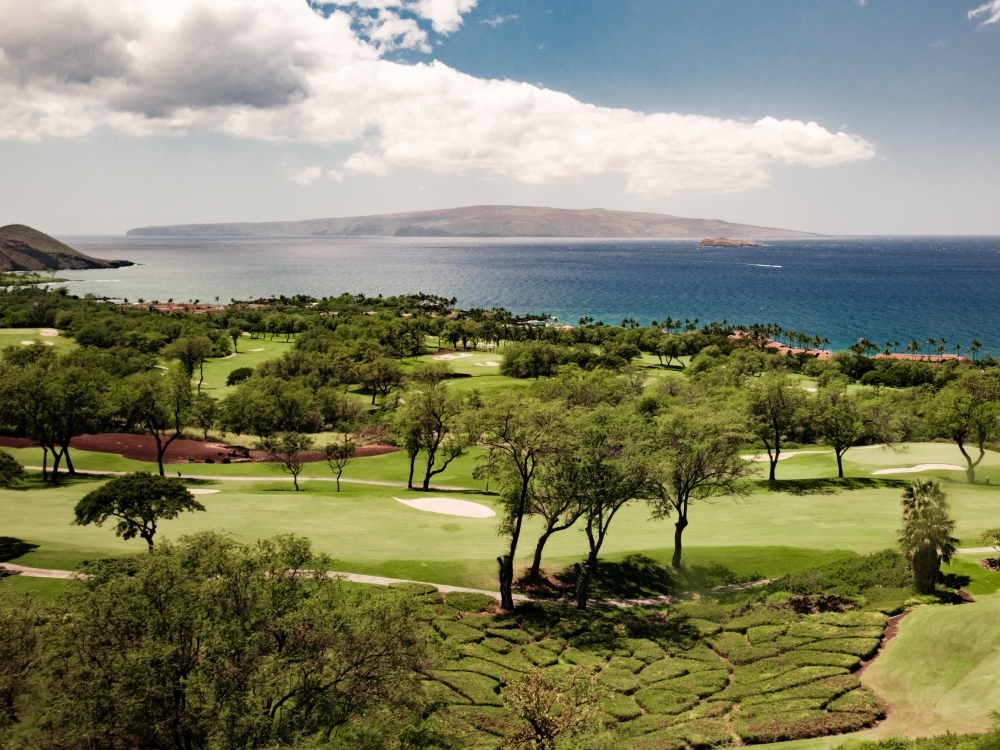 Lush green golf course with a beautiful background of the ocean and mountains