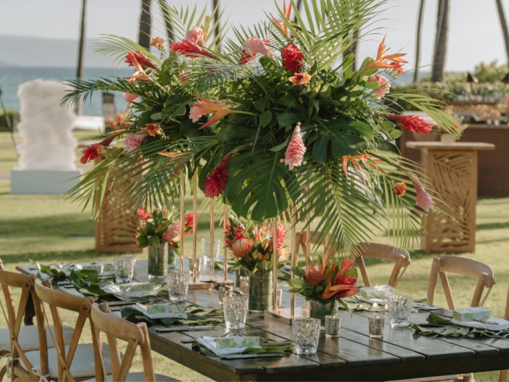 A tropical floral arrangement on a table at an outdoor wedding