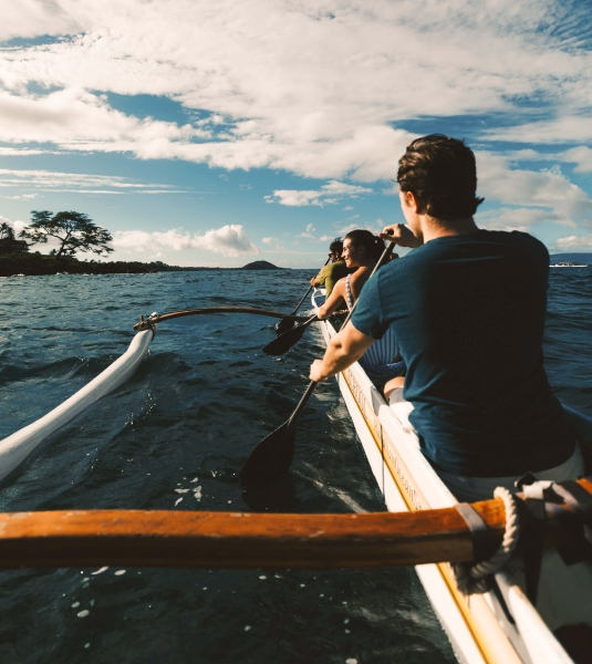 a person in an outrigger canoe against faces the open water below a cloudy sky